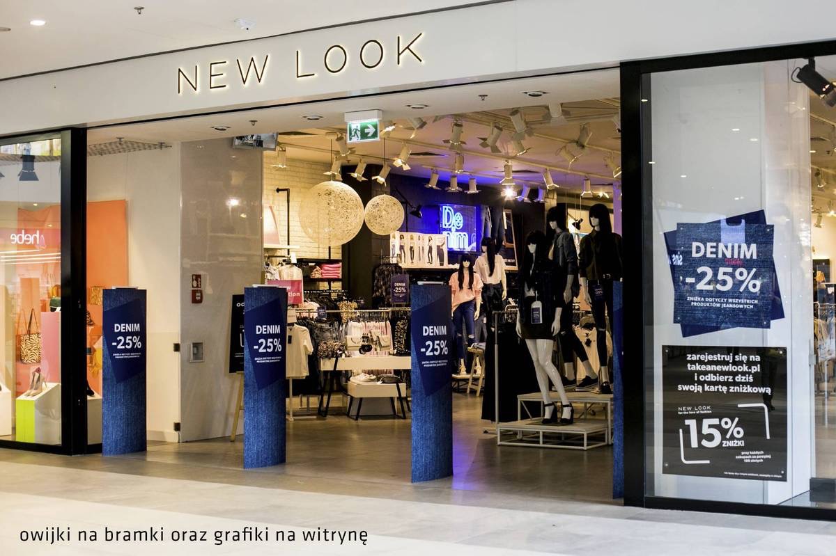 Wejście do sklepu odzieżowego New Look z grafikami promocyjnymi na bramkach i witrynie, informującymi o 25% zniżce na odzież jeansową oraz 15% zniżce po rejestracji.