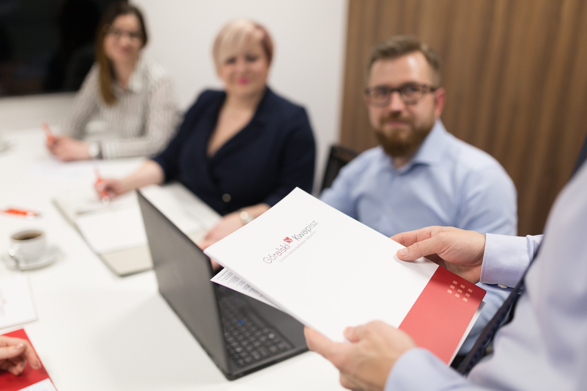 Prezentacja oferty firmy Gorski Kwapisz podczas spotkania biznesowego, w tle laptop i notatki.