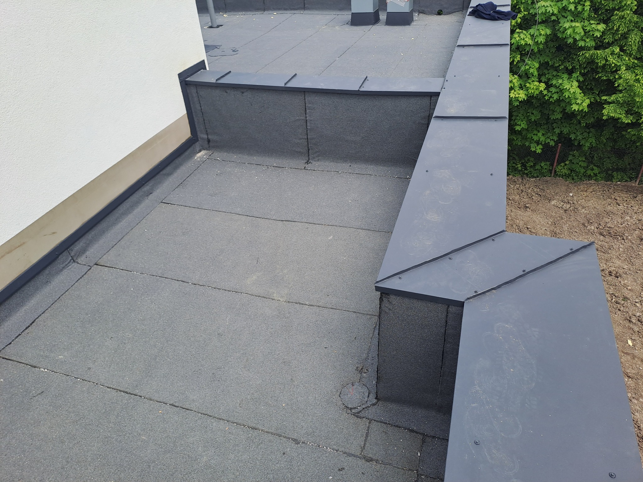 Płaski dach pokryty papą termozgrzewalną z obróbkami blacharskimi, widok z góry.