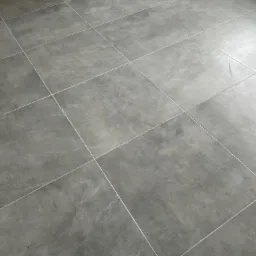 Ułożona, gładka, szara podłoga z płytek ceramicznych z jasnymi fugami, widziana pod kątem.