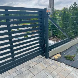 Nowoczesna, pozioma brama wjazdowa z automatyką i lampą ostrzegawczą, zainstalowana w Kamionnej, z widocznym fragmentem posesji i kostką brukową.