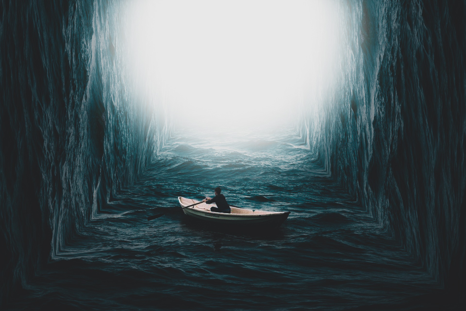 Człowiek płynący łódką przez wąski, ciemny kanał wodny z wysokimi, teksturowanymi ścianami, oświetlony intensywnym światłem na końcu tunelu.
