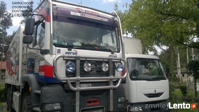 Dwa białe samochody ciężarowe, jeden z napisem 'verva' i flagą Polski, stoją obok siebie na zewnątrz, z zielonymi drzewami w tle. Widoczne dodatkowe reflektory.