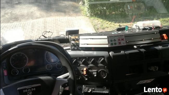 Wnętrze kabiny ciężarówki MAN z widoczną deską rozdzielczą, kierownicą i zamontowanym urządzeniem diagnostycznym. Widok z perspektywy kierowcy, światło dzienne.