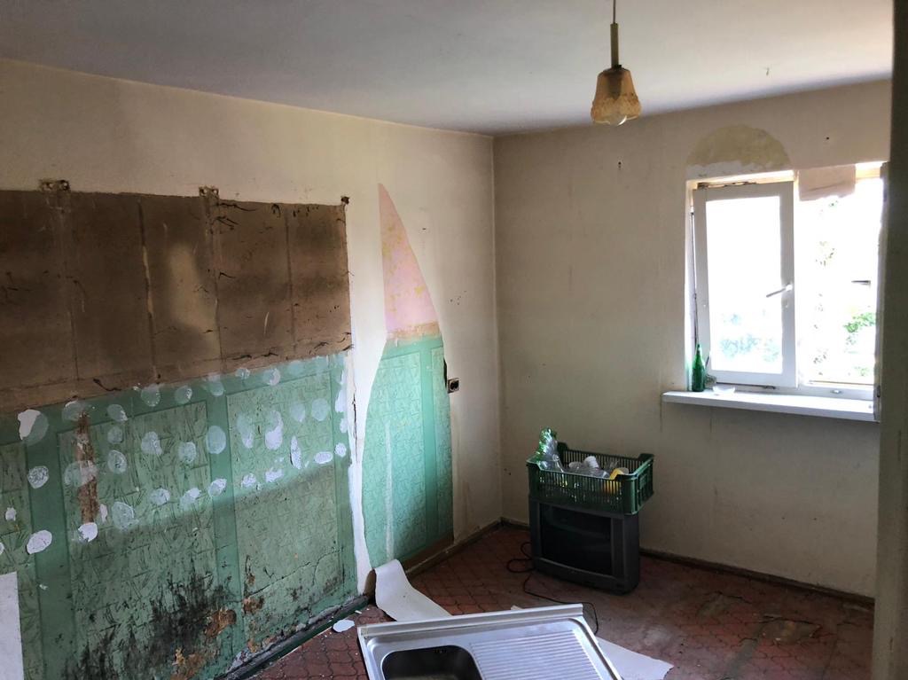 Kuchenne wnętrze w Ławach w trakcie demontażu starych płytek ściennych, z widocznymi śladami kleju i fragmentami oderwanej tapety, przygotowywane do dalszych prac wykończeniowych.