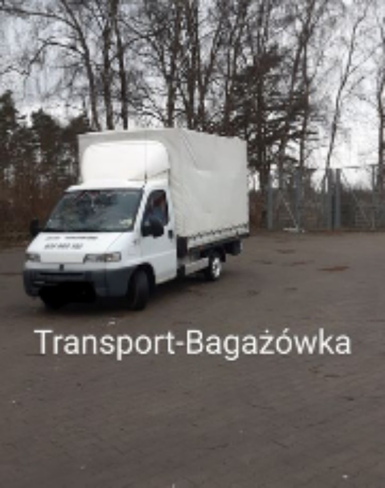 Biały bus z plandeką na parkingu w pochmurny dzień, widoczne drzewa w tle.