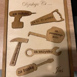 Drewniana tabliczka z wygrawerowanymi narzędziami i napisem 'Kochany Tatusiu! Dziękuję Ci...' z dedykacjami 'za miłość', 'za to, że jesteś', 'za poświęcony czas', 'za pierwszego guza', 'za...