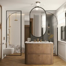 Pina-Studio.pl Natalia Piątkowska - Elegancka łazienka z drewnianą szafką pod umywalką, kabiną prysznicową w czarnej ramie i owalnym lustrem. Parkiet w jodełkę i stonowana kolorystyka.