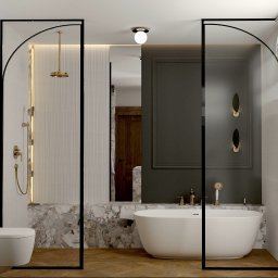 Pina-Studio.pl Natalia Piątkowska - Elegancka łazienka z wolnostojącą wanną, marmurowym wykończeniem i złotą armaturą, oddzielona czarnymi, łukowatymi przeszkleniami. Parkiet w jodełkę.