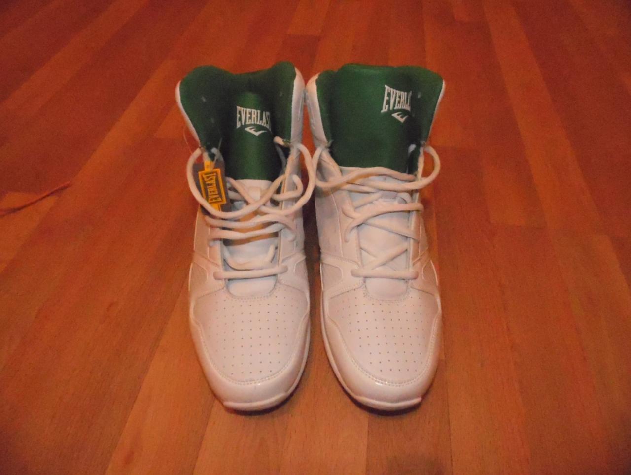 Para białych, skórzanych butów sportowych marki Everlast z zielonym wnętrzem, sznurowane, na drewnianej podłodze.