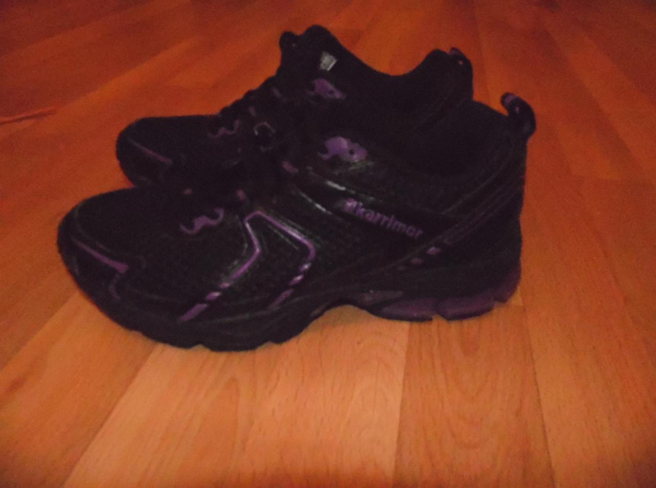 Para czarnych butów sportowych Karrimor z fioletowymi akcentami, leżących na drewnianej podłodze.