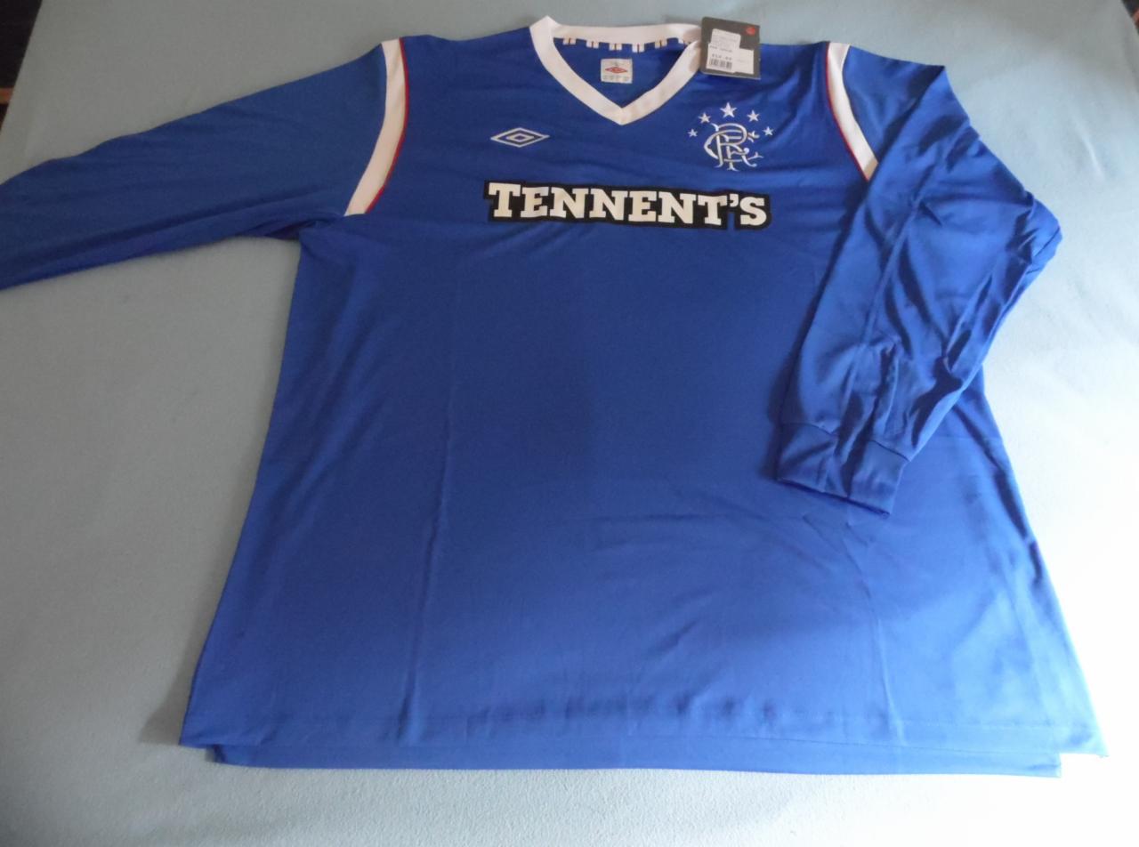 Niebieska koszulka piłkarska z długim rękawem, logo drużyny i napisem sponsora Tennent's, leżąca na jasnym tle.