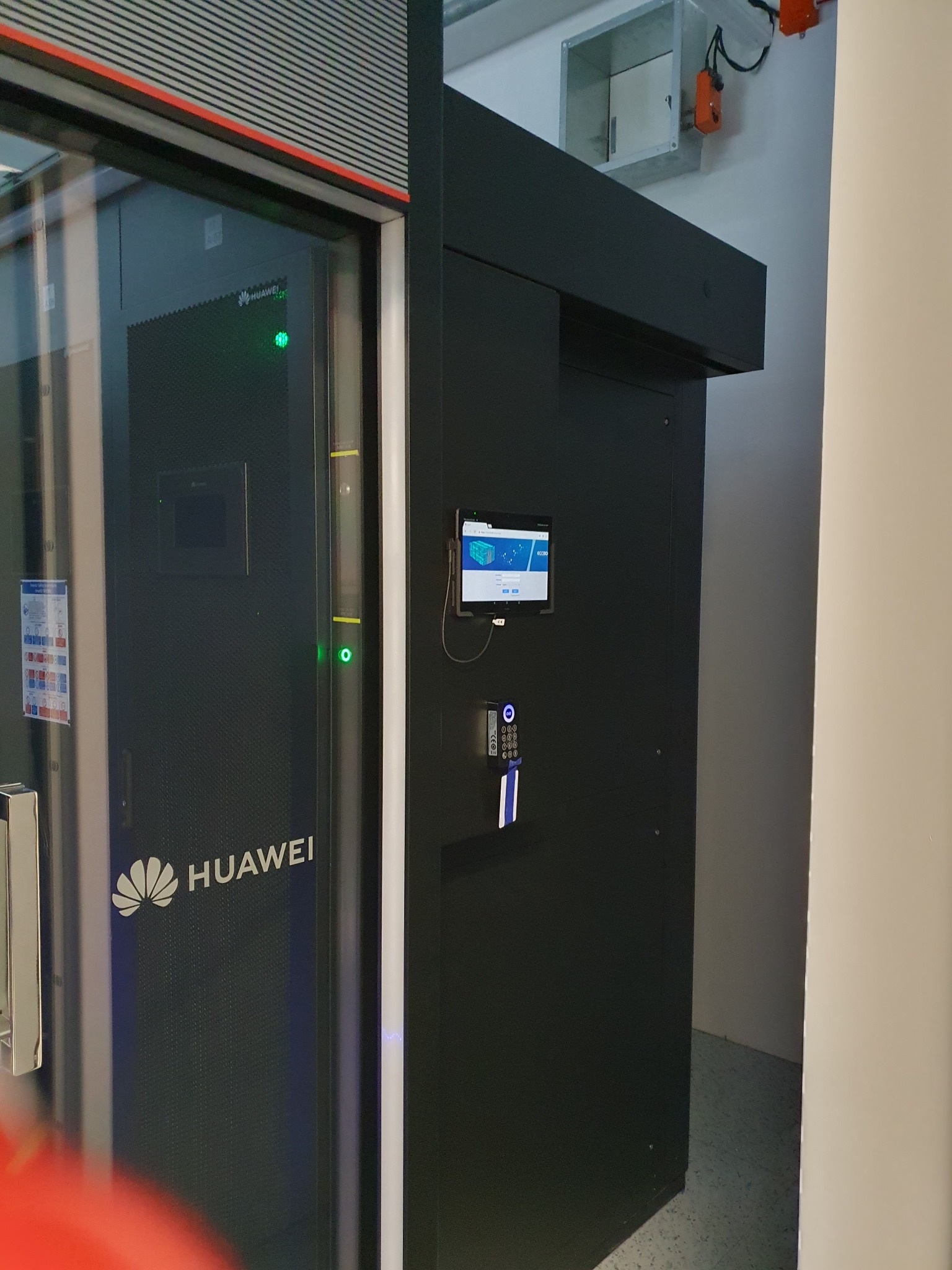 Czarna szafa serwerowa Huawei z panelem dotykowym i czytnikiem kart dostępu w pomieszczeniu technicznym.