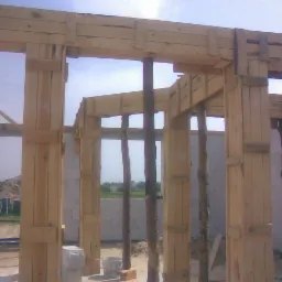 Drewniany szalunek pod budowę ścian domu z betonu komórkowego, widoczne podpory z surowych pni drzew