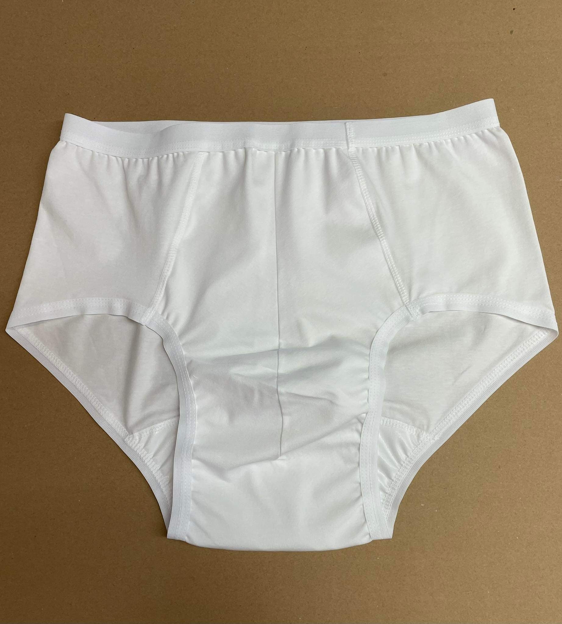Para białych, bawełnianych, męskich slipów na brązowym tle, widoczne szwy i elastyczna gumka w pasie.