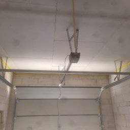 Usługi Remontowo budowlane Mateusz Kwiecień - Montaż sufitu z płyt kartonowo-gipsowych w garażu z widocznym mechanizmem otwierania bramy garażowej.