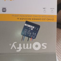 ELWAS ŁUKASZ WĄSIK - Pudełko z odbiornikiem LED Dimmer Receiver io firmy Somfy, z widocznym urządzeniem i schematem podłączenia przewodów.