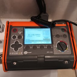 ELWAS ŁUKASZ WĄSIK - Miernik Sonel MPI-530 z wyświetlanymi wynikami pomiaru impedancji pętli zwarcia ZL-N=0,705Ω, leżący na umywalce w łazience.