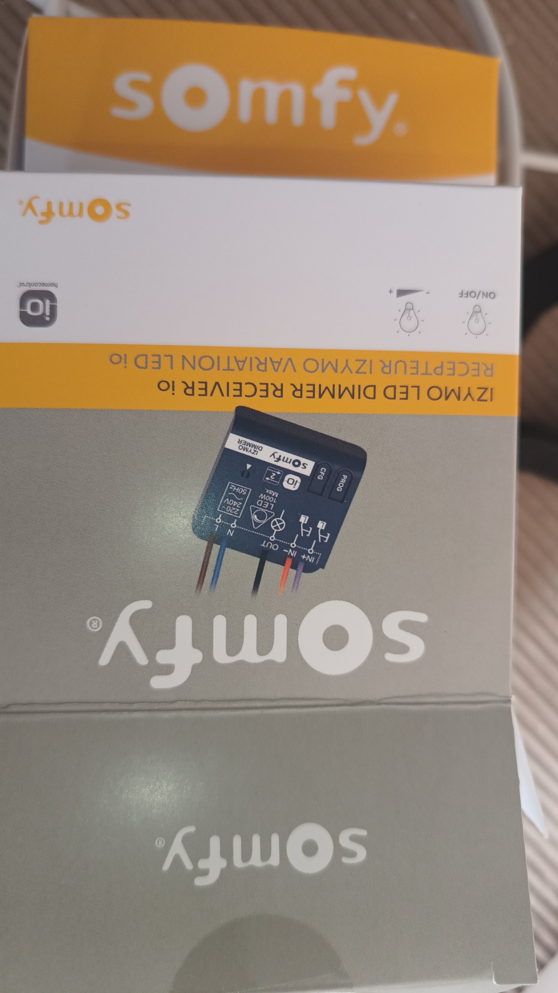 Pudełko z odbiornikiem LED Dimmer Receiver io firmy Somfy, z widocznym urządzeniem i schematem podłączenia przewodów.