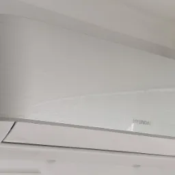 Świeżo zamontowany, srebrno-biały klimatyzator Hyundai na jasnej ścianie, widoczne subtelne szczotkowane wykończenie obudowy.