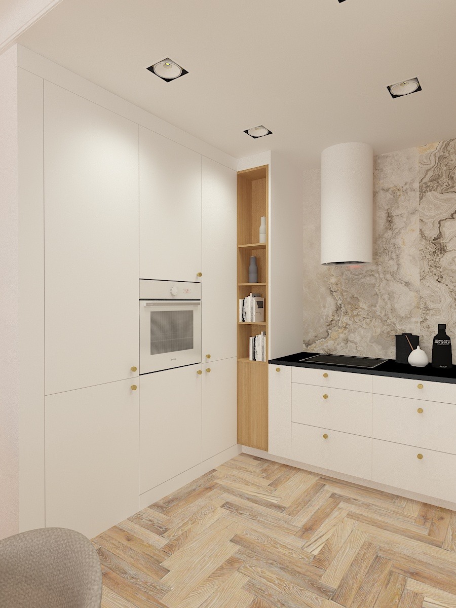 Wnętrze nowoczesnej kuchni z białymi szafkami, złotymi gałkami i parkietem w jodełkę, z marmurowym panelem na ścianie i zabudowaną półką z książkami.