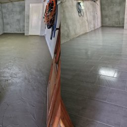 GOLD RENOVATION - Porównanie stanu podłogi przed i po: wylewka wyrównująca w surowym stanie po lewej, ułożone szare płytki podłogowe po prawej stronie, widoczne akcesoria i narzędzia w tle.