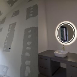 GOLD RENOVATION - Po lewej: ściana w trakcie szpachlowania, widoczne fragmenty z nałożoną gładzią. Po prawej: wykończona łazienka z podświetlanym lustrem i umywalką na szarej szafce.