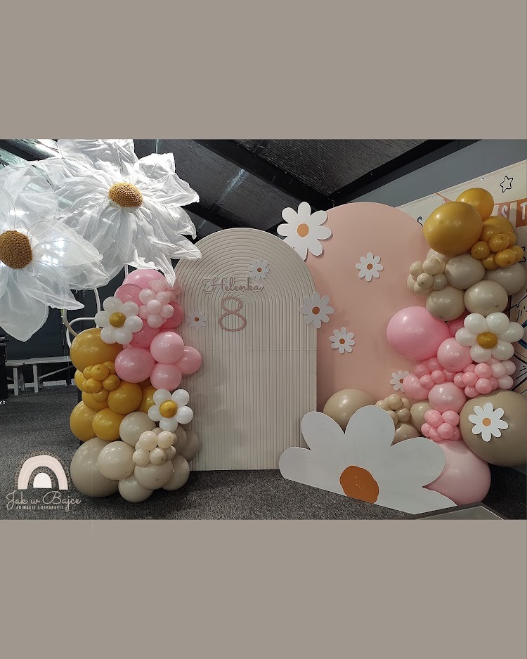 Dekoracja urodzinowa w pastelowych kolorach z balonami, kwiatami i napisem 'Helenka 8' na tle w kształcie łuku.