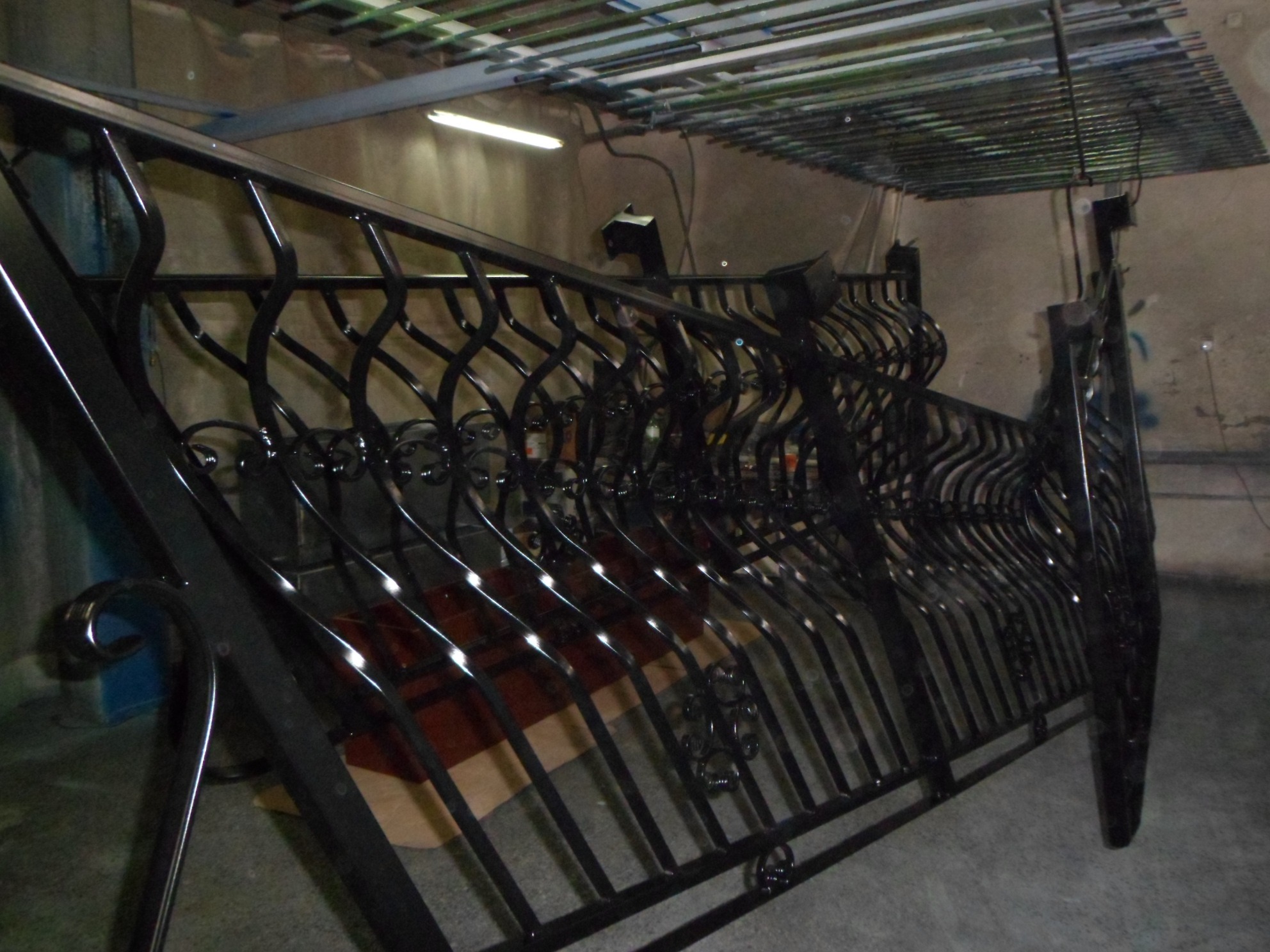Świeżo pomalowana, czarna, ozdobna balustrada z metalu w warsztacie w Gdańsku, jeszcze schnąca pod lampami.