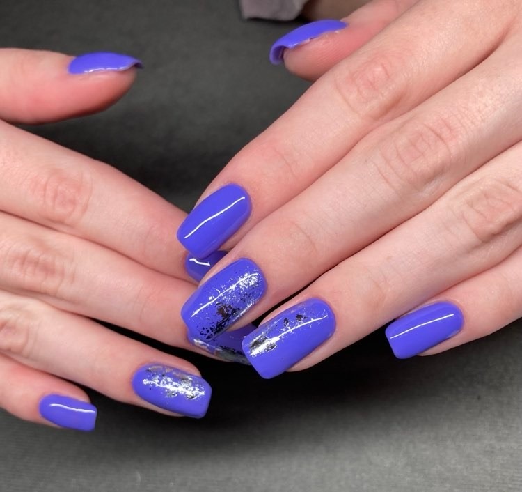 Manicure hybrydowy w odcieniu fioletu z folią transferową na paznokciach o kwadratowym kształcie.