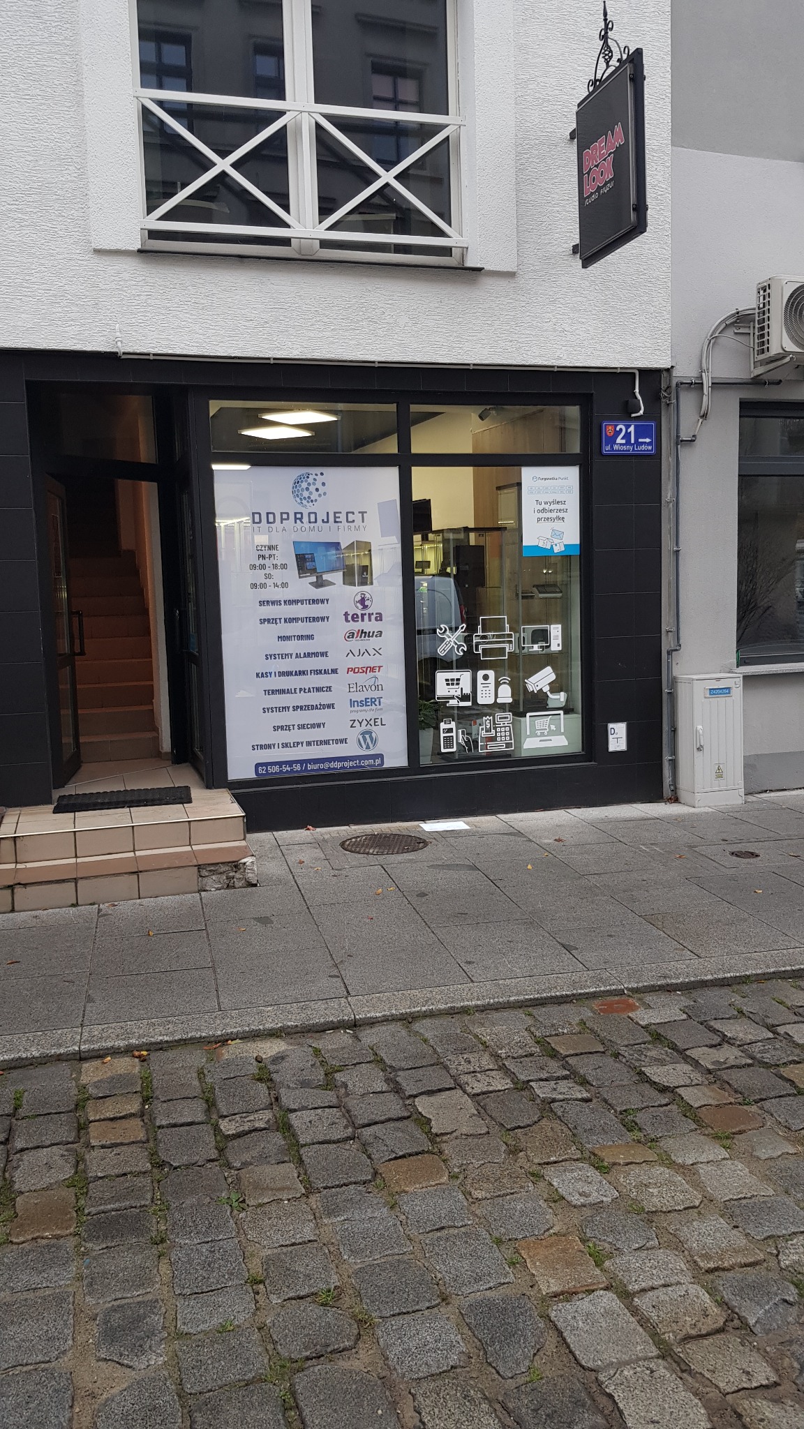 Fasada budynku firmy IT z witryną prezentującą ofertę: serwis komputerowy, sprzęt komputerowy, monitoring, systemy alarmowe, kasy fiskalne, terminale płatnicze, systemy sprzedażowe, sprzęt sieciowy...