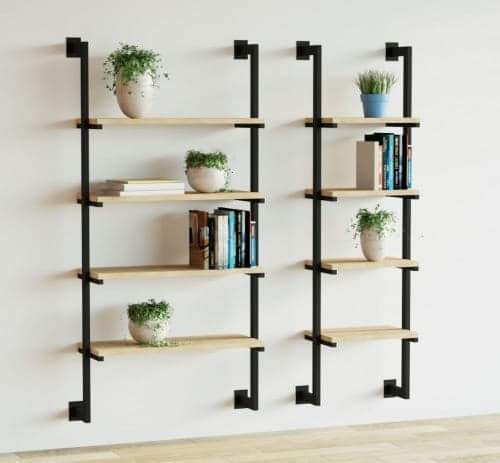 Dwie nowoczesne półki ścienne z czarnymi metalowymi wspornikami i jasnymi drewnianymi półkami, na których stoją książki i rośliny doniczkowe w białych i niebieskich osłonkach.