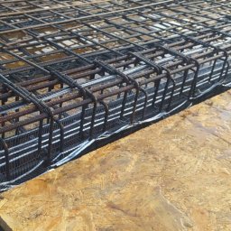 BiałoBud - Siatka zbrojeniowa ułożona na płycie szalunkowej, przygotowana do zalania betonem.