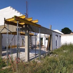 BiałoBud - Budowa domu z białych bloczków, widoczne zbrojenia i podpory stropu, otoczenie w stanie surowym.