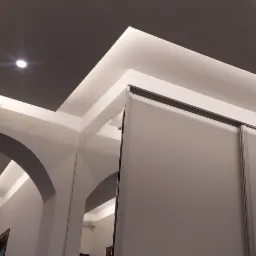 Nowoczesne wnętrze mieszkania z podwieszanym sufitem z oświetleniem LED, łukowym przejściem i szafą wnękową z przesuwnymi drzwiami.