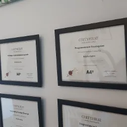 Ściana z czterema oprawionymi certyfikatami ukończenia kursów: Dietetyka i suplementacja w sporcie, Programowanie Treningowe, Fundamenty Treningu Siłowego, Diagnostyka w Treningu, wszystkie...