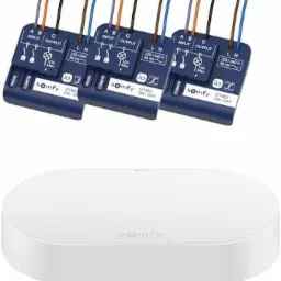 Trzy niebieskie moduły sterujące oświetleniem marki Somfy z podłączonymi przewodami i biała centrala sterująca, widok z góry, oświetlenie studyjne.