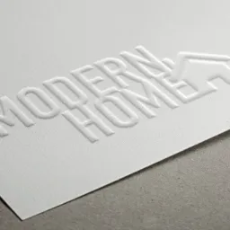 Eleganckie tłoczenie logo 'Modern Home' na białym, fakturowanym papierze, z subtelnym cieniowaniem.