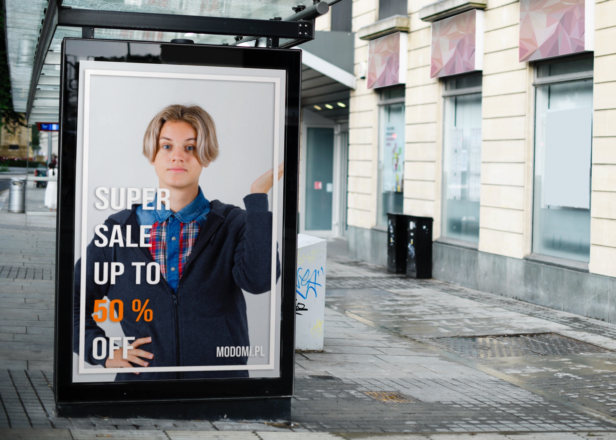 Plakat reklamowy w wiacie przystankowej z młodym mężczyzną i napisem 'SUPER SALE UP TO 50% OFF' na tle ulicy z budynkami i koszami na śmieci.