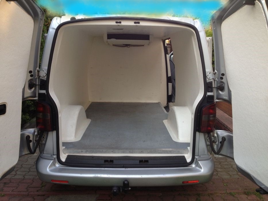 Wnętrze dostawczego samochodu chłodni z otwartymi drzwiami, widoczny agregat chłodniczy zamontowany pod sufitem.