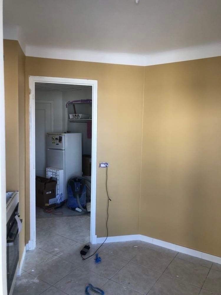 Pokój po malowaniu ścian na kolor złoty, widoczne niedociągnięcia na podłodze i gniazdko elektryczne bez osłony.