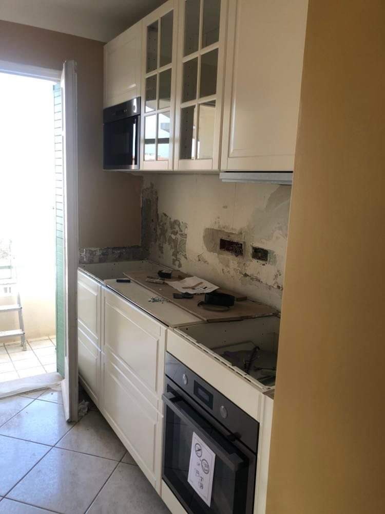 Białe szafki kuchenne w trakcie montażu w Radomiu, widoczne niedoskonałości ściany przed wykończeniem.