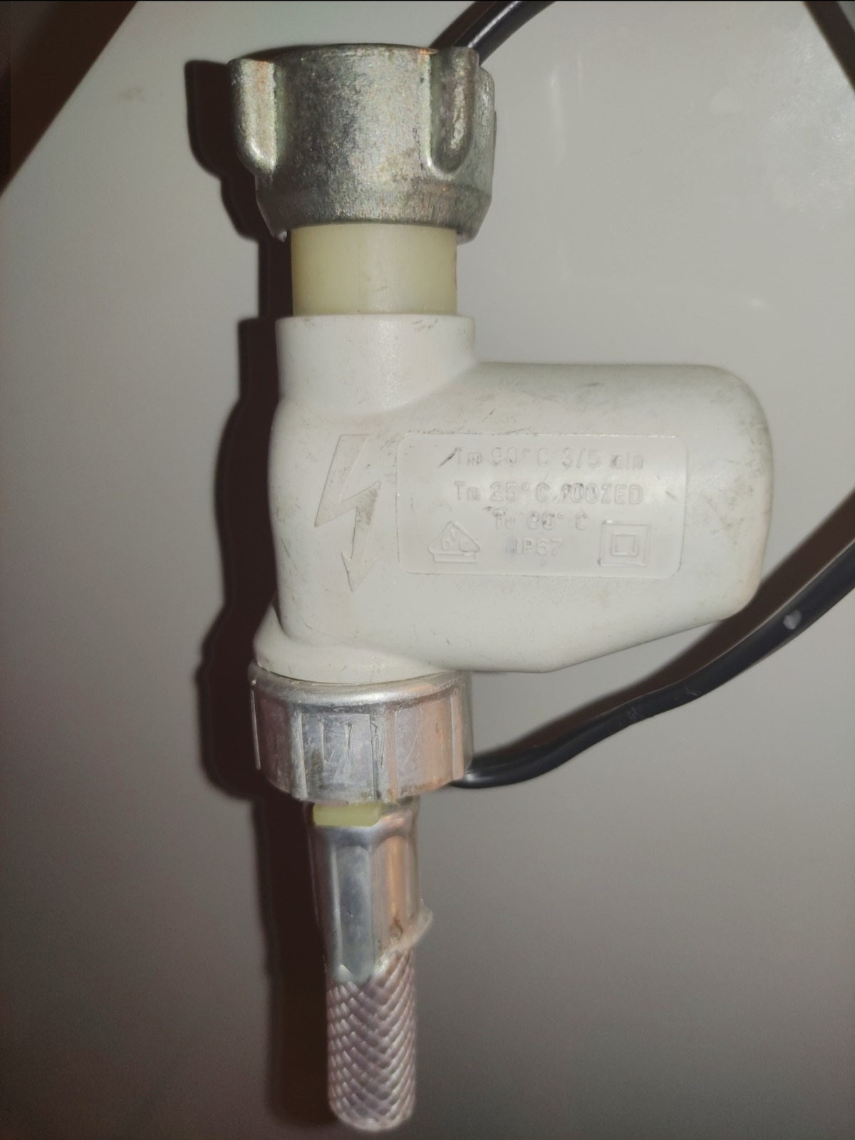 Zawór termostatyczny z metalowymi złączkami i widocznymi oznaczeniami technicznymi na plastikowej obudowie.