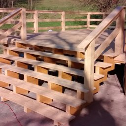 Altany tarasy - Surowe drewniane schody prowadzące na podest, widoczne narzędzia i kabel zasilający, wskazujące na trwające prace wykończeniowe.