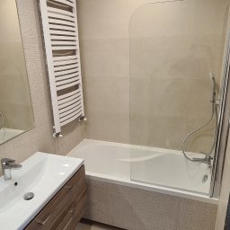 Part Home - Nowoczesna łazienka w beżowych odcieniach z wanną z parawanem, umywalką z szafką z drewnopodobnym frontem i grzejnikiem drabinkowym.