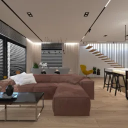 Nowoczesny salon z brązową sofą narożną, stolikiem kawowym z czarnym blatem i metalową ramą, oraz otwartą kuchnią z barkiem i hokerami. W tle widoczne schody i duże okna z żaluzjami.