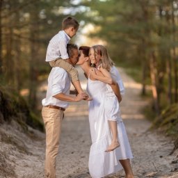 Foto 3 - Rodzinne ujęcie w lesie: ojciec z synem na ramionach całuje matkę z córką na plecach, wszyscy boso na piaszczystej ścieżce, w bieli.