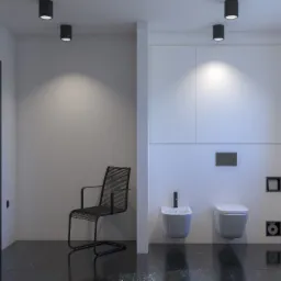 Minimalistyczna łazienka z czarną podłogą imitującą marmur, białe ściany z wbudowaną szafką, wisząca toaleta i bidet, czarne dodatki oraz krzesło ze sznurka w rogu.