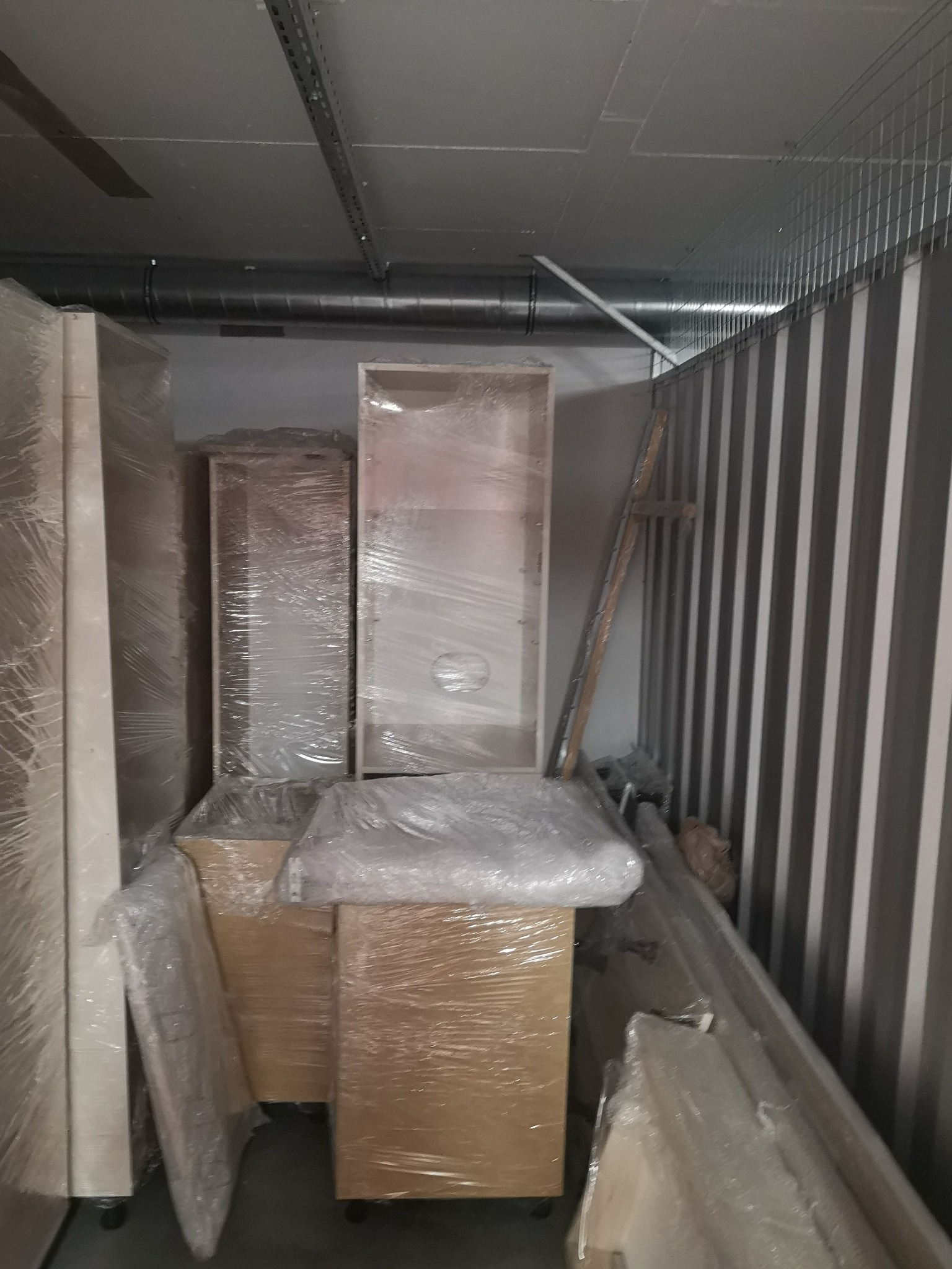 Meble zapakowane w folię stretch, przygotowane do transportu w magazynie z metalowymi ścianami.