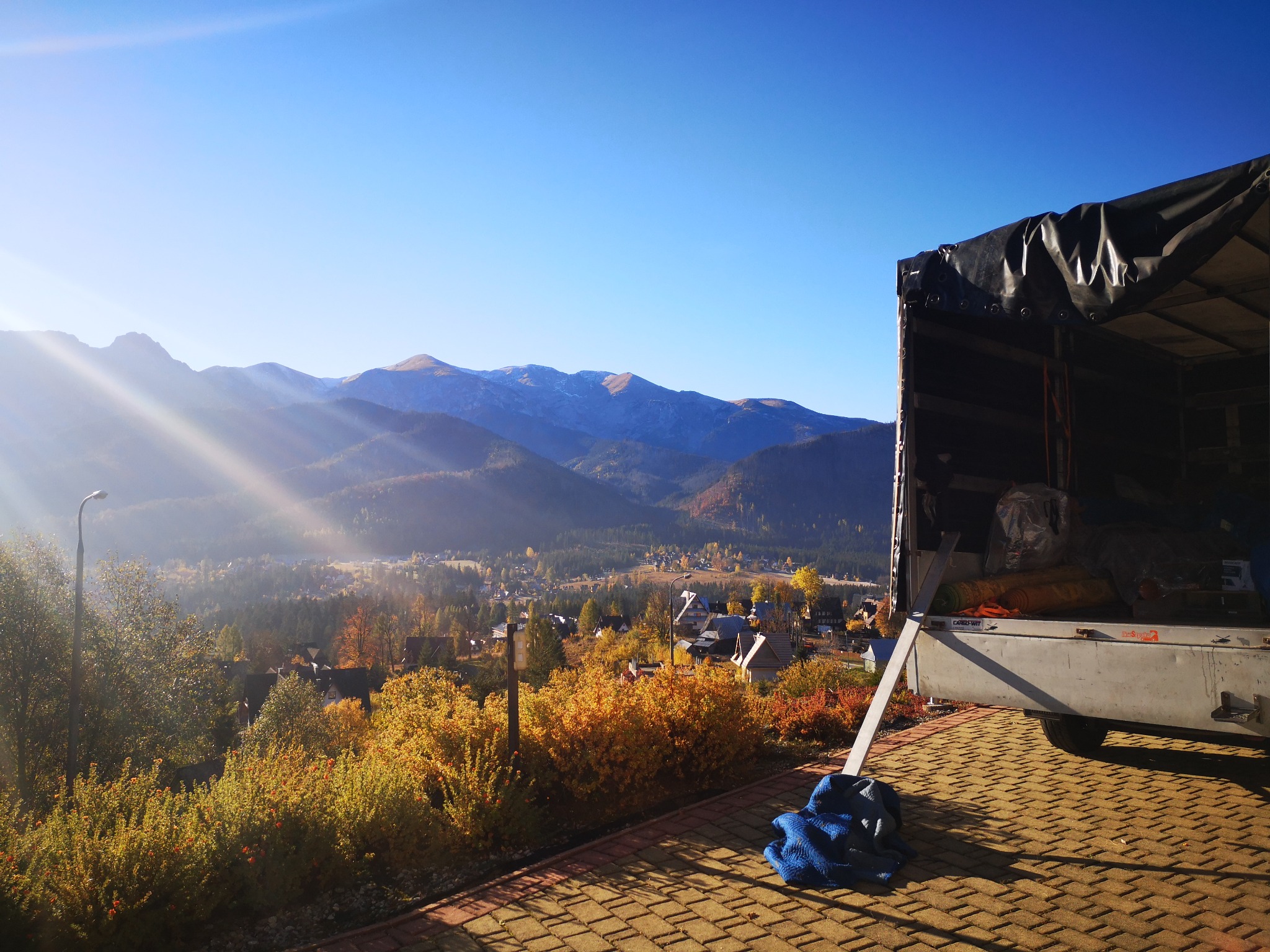 Otwarta paka samochodu dostawczego z ładunkiem na tle górskiego krajobrazu w słoneczny dzień.